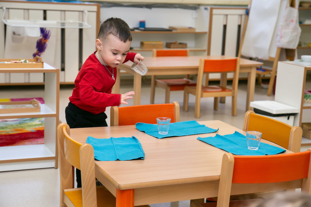 Montessori nursery - child helping with setting up the table